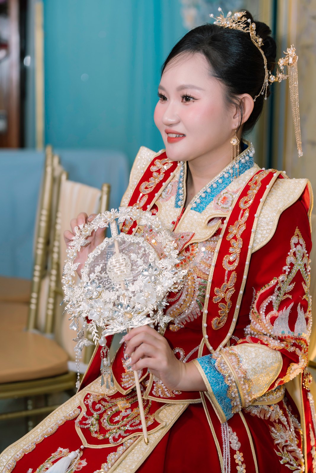 Cô dâu trong áo cưới truyền thống đỏ thêu kim tuyến cầm quạt trang trí