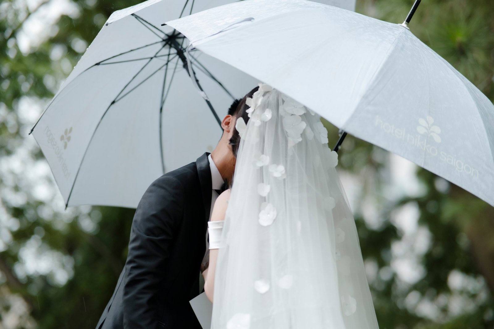 Cô dâu chú rể trao nhau nụ hôn dưới hai chiếc ô giữa khoảnh khắc rất thật