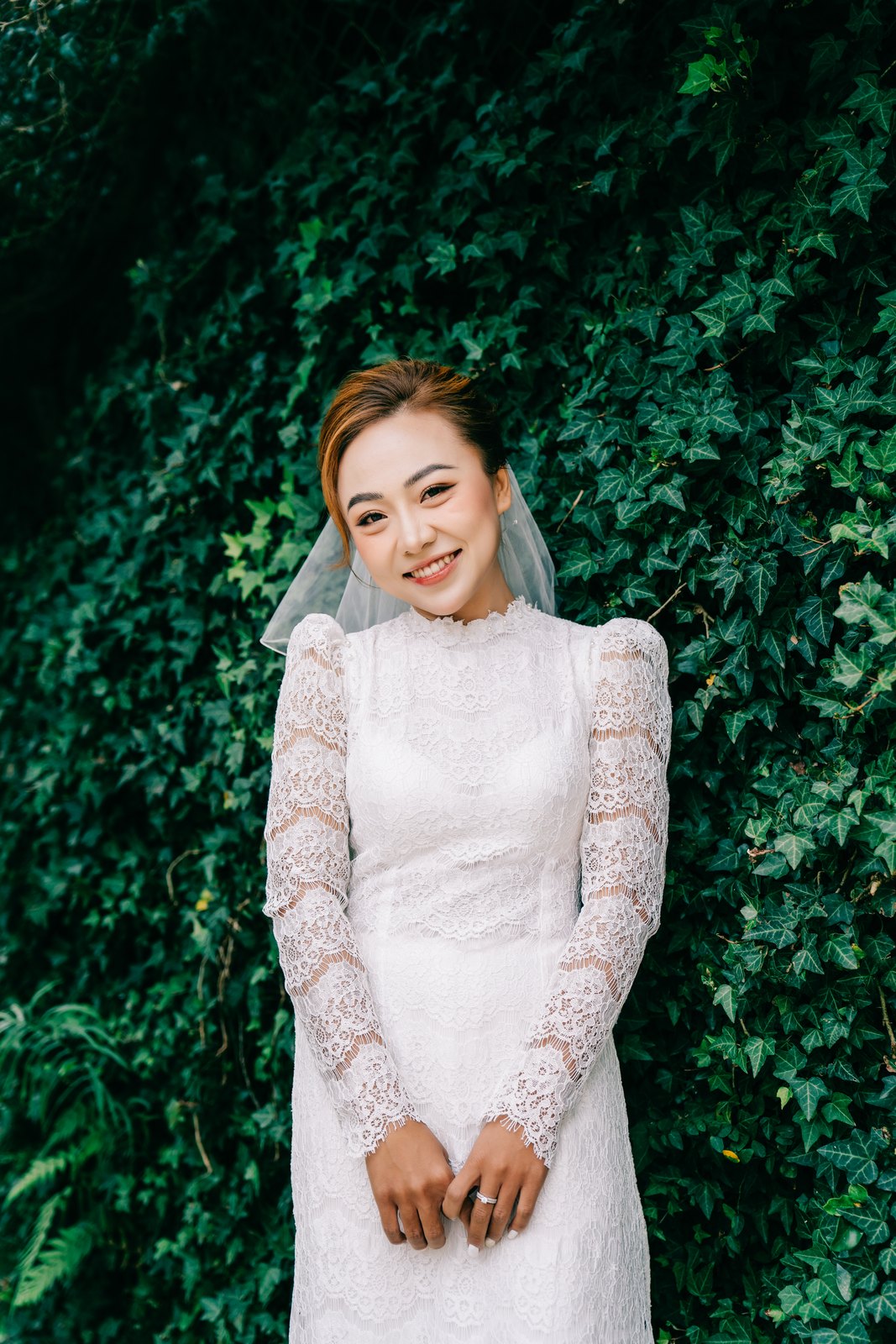 Cô dâu áo dài trắng rạng rỡ bên tường lá xanh mướt, nắng dịu