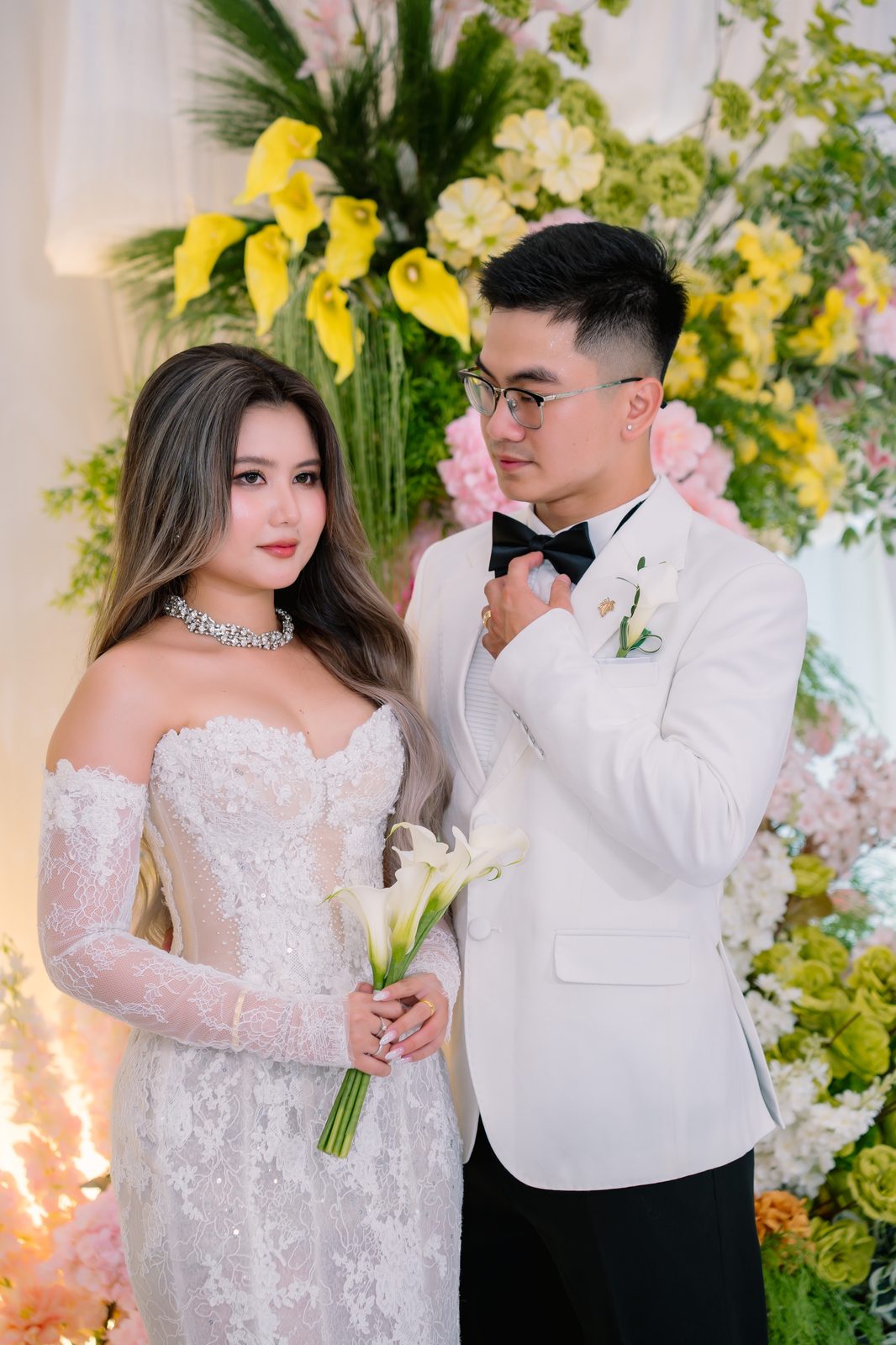 Cô dâu chú rể Huỳnh Nhi và Hoàng Nhật trong váy cưới trắng và vest tại tiệc cưới buổi tối